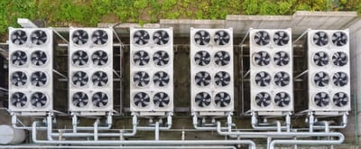 Aerial view of six industrial HVAC units arranged in two rows, with visible fans and pipes, set against a grassy background. - Southland Mechanical: Industrial Strength HVAC