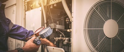 A technician checks HVAC equipment with pressure gauges next to a large fan. - Southland Mechanical: Industrial Strength HVAC